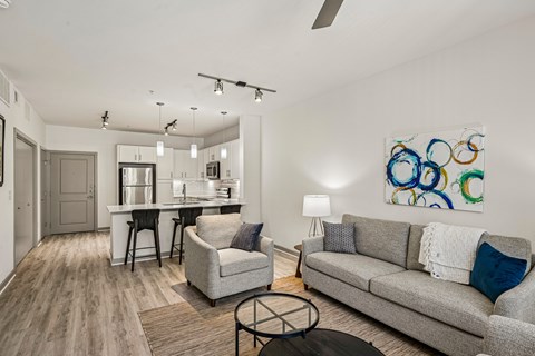 A modern living room with a grey couch, a white coffee table, and a painting on the wall.