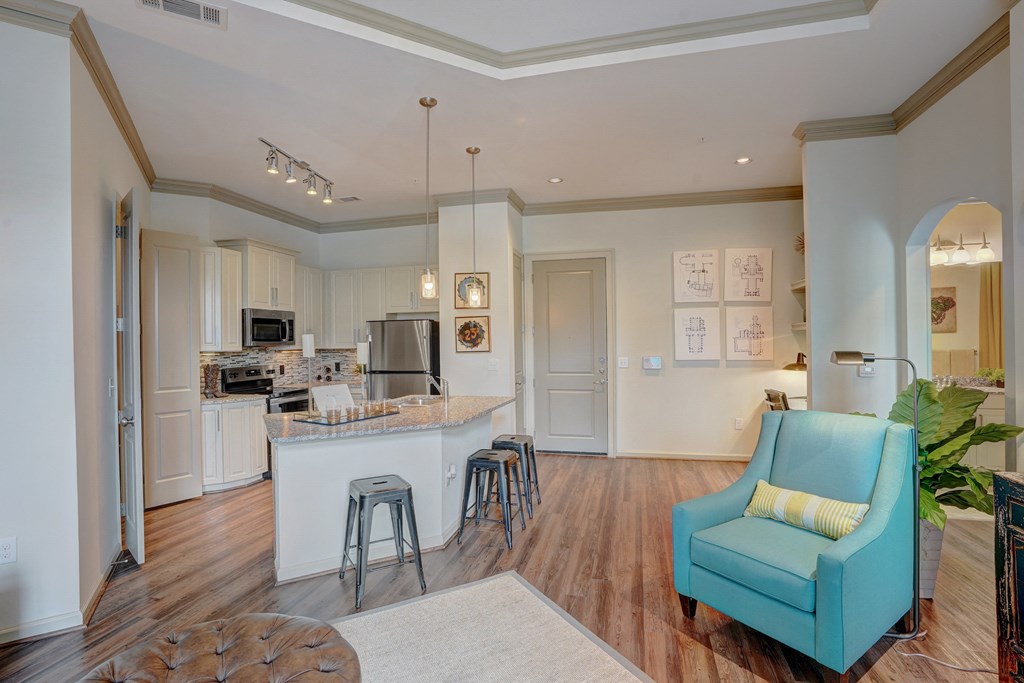 a living room with a kitchen with a bar and a blue chair