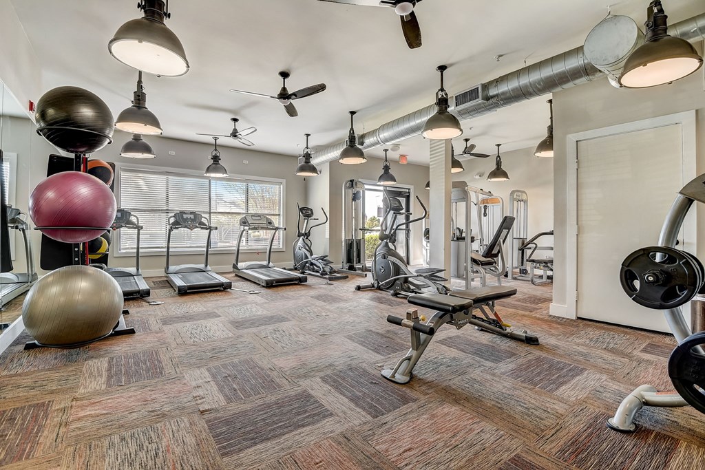a gym with weights machines and lights on the ceiling