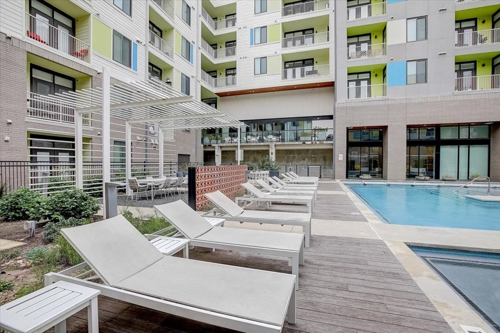 a row of white lounge chairs next to a swimming pool