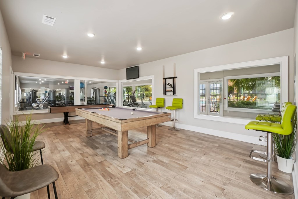 A room with a pool table and a bar area.