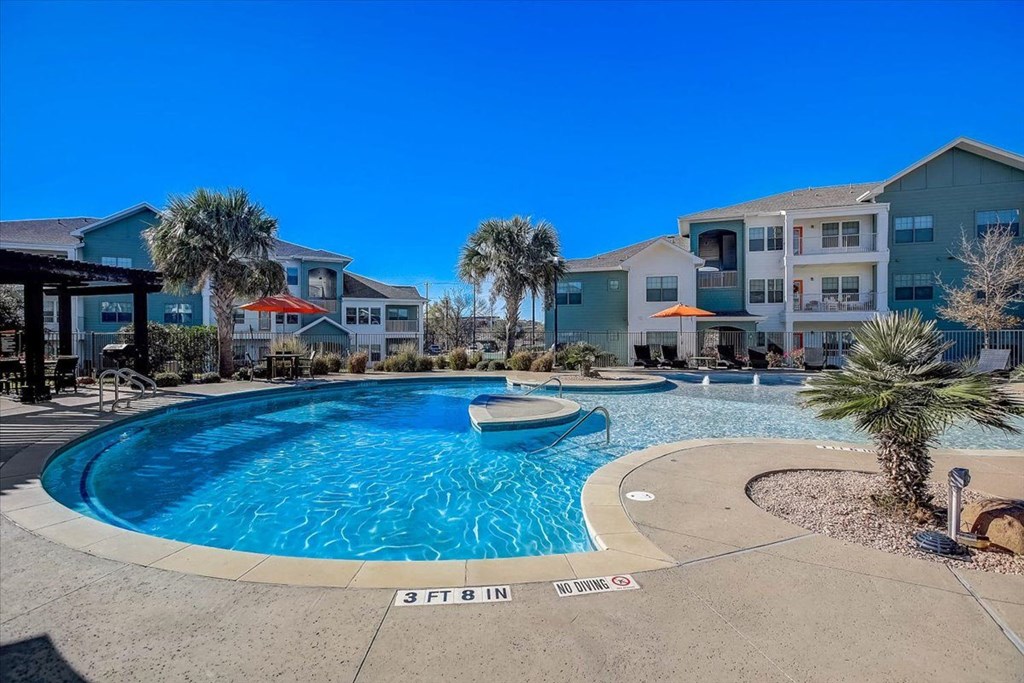 a swimming pool with palm trees in front of an apartment building