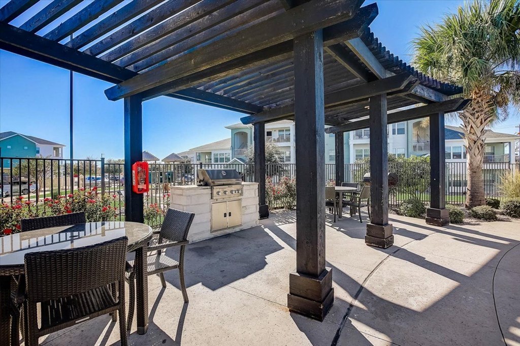 a patio with a grill and tables and a pergola