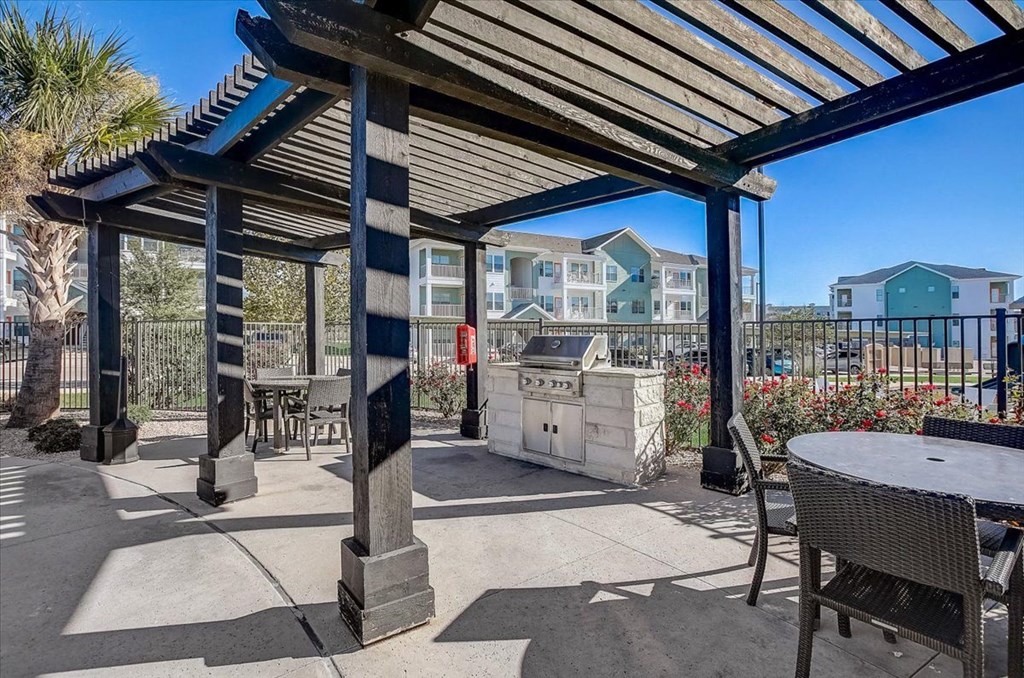 a patio with a grill and a table and chairs
