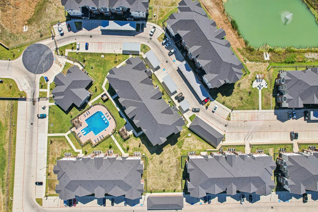 A bird's eye view of a residential area with houses and a swimming pool.