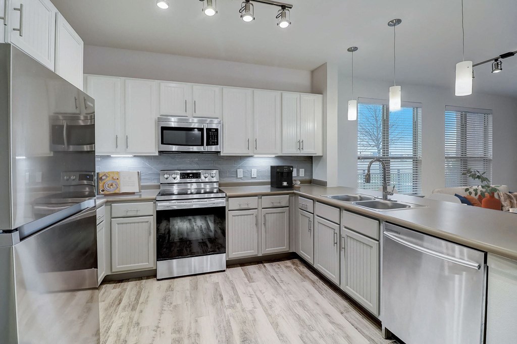 an empty kitchen with white cabinets and stainless steel appliances