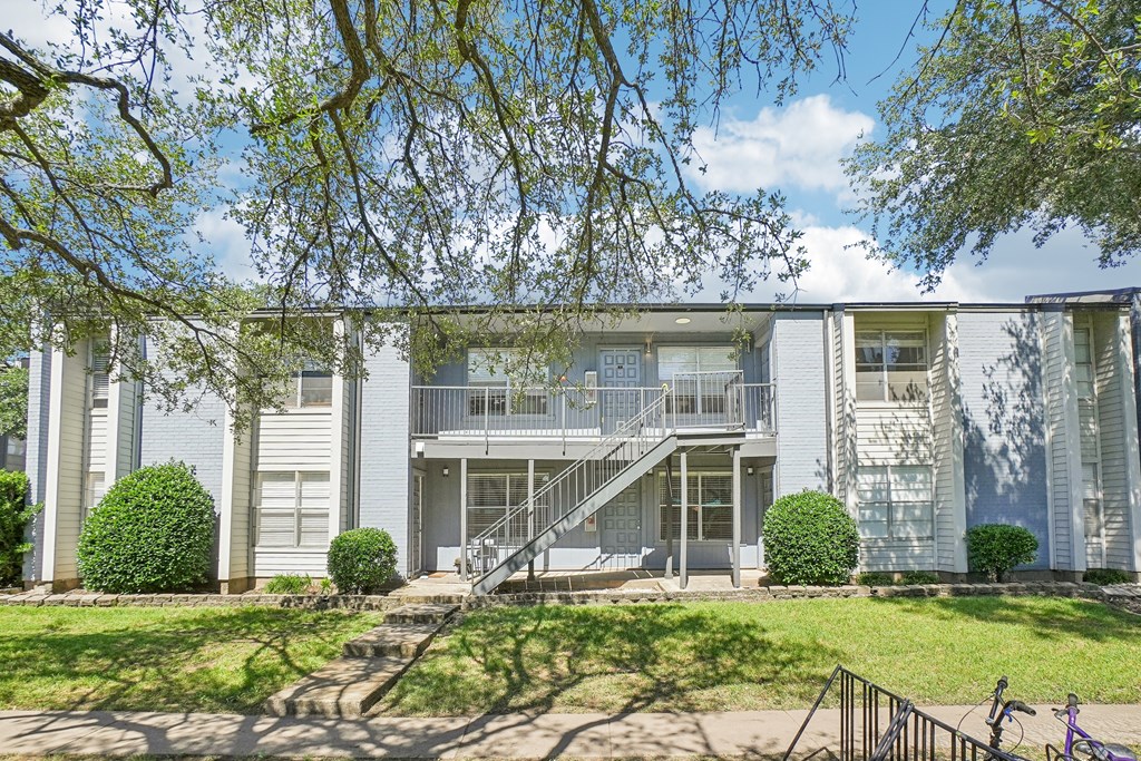 A white building with a balcony and stairs leading to it.