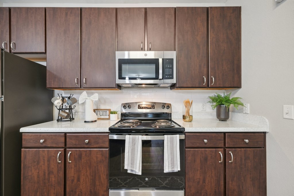 A kitchen with a black stove top oven and wooden cabinets.