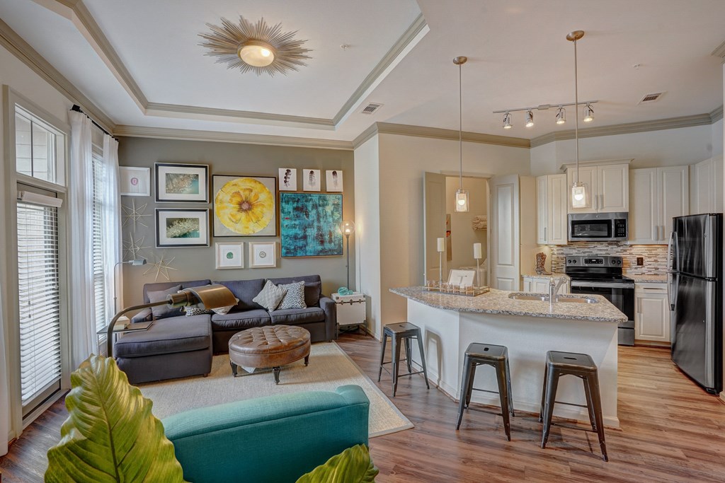 a living room with a kitchen and a bar with stools