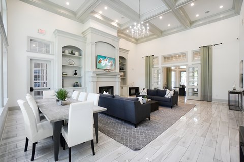 Creekside 121 clubhouse lounge with coffered ceiling, chandelier, fireplace, and dining area.