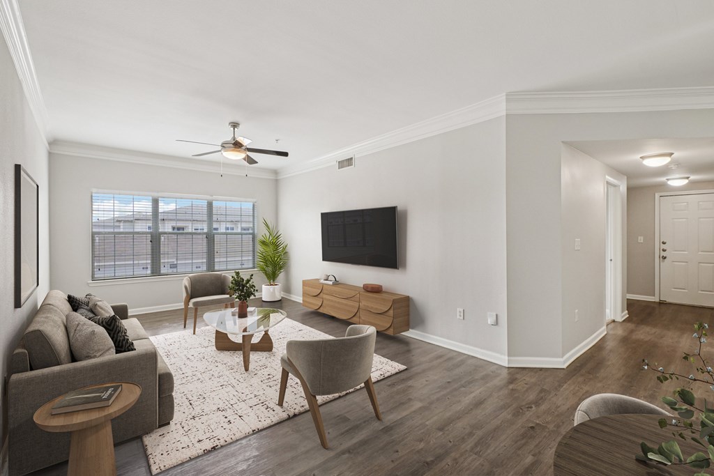 A living room with a grey couch, a wooden coffee table, and a flat screen TV mounted on the wall.