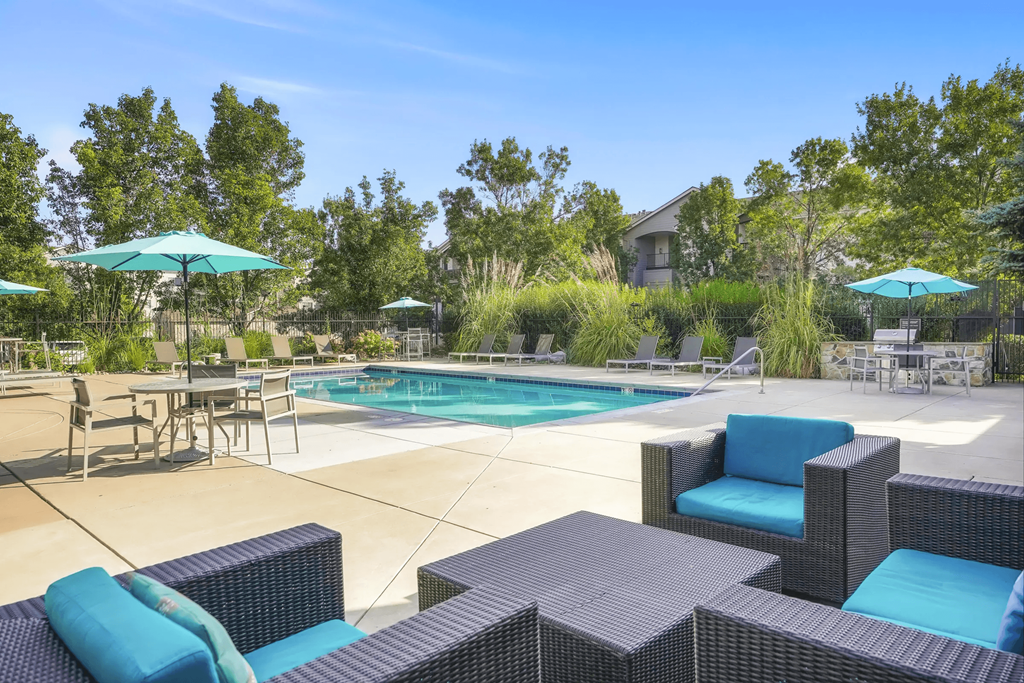 a swimming pool with patio furniture and umbrellas