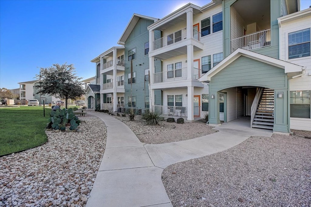an exterior view of an apartment building with a sidewalk