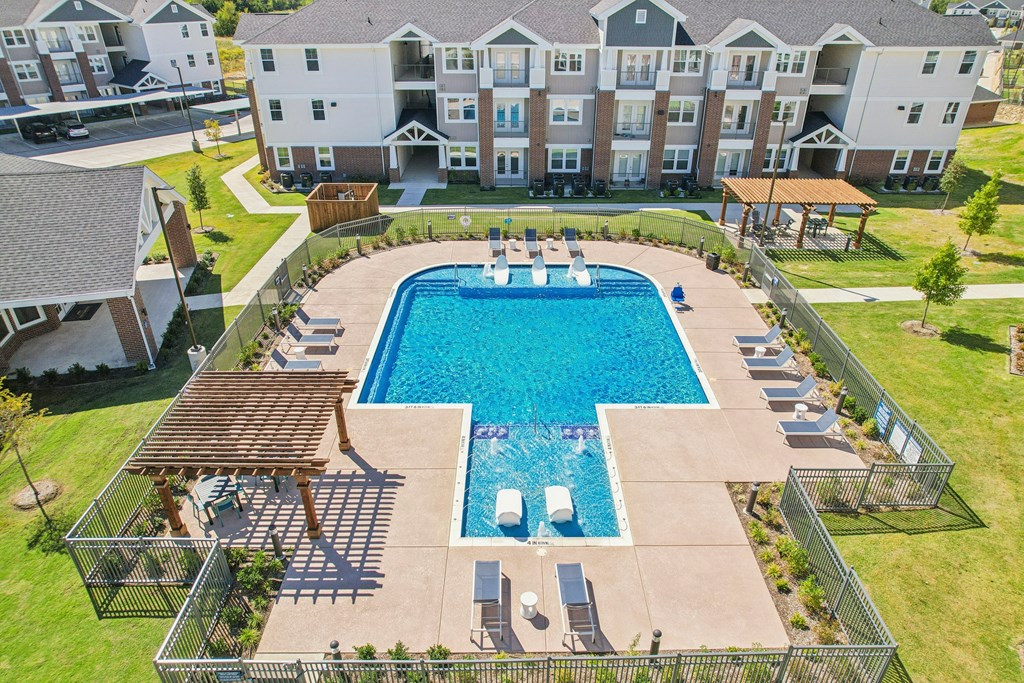 A large swimming pool surrounded by a fence and a building in the background.