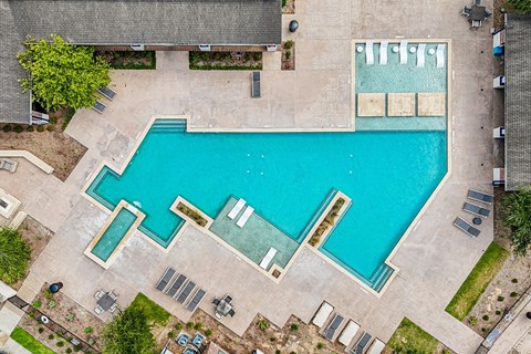 An aerial view of a swimming pool surrounded by a concrete area.
