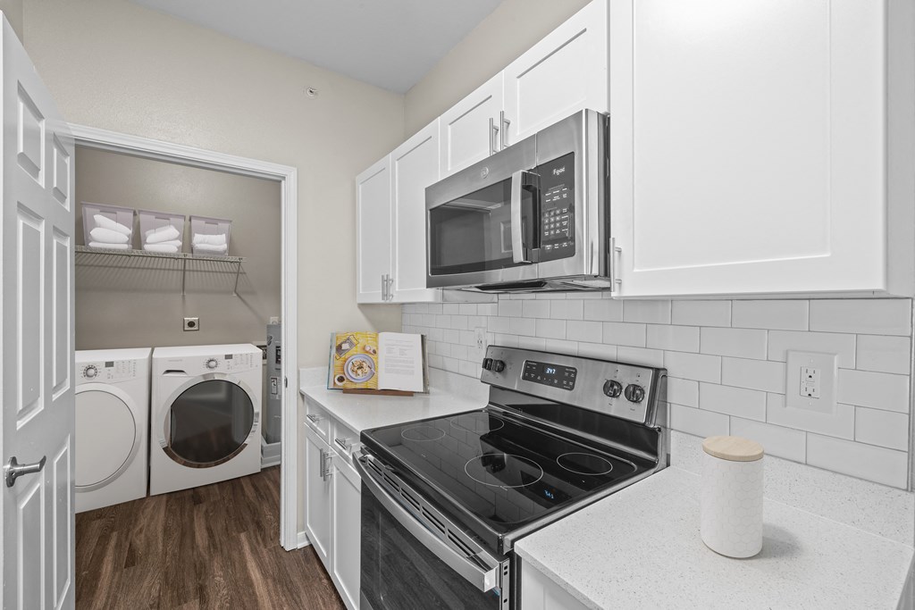 a kitchen with white cabinets and black appliances and a white washer and dryer