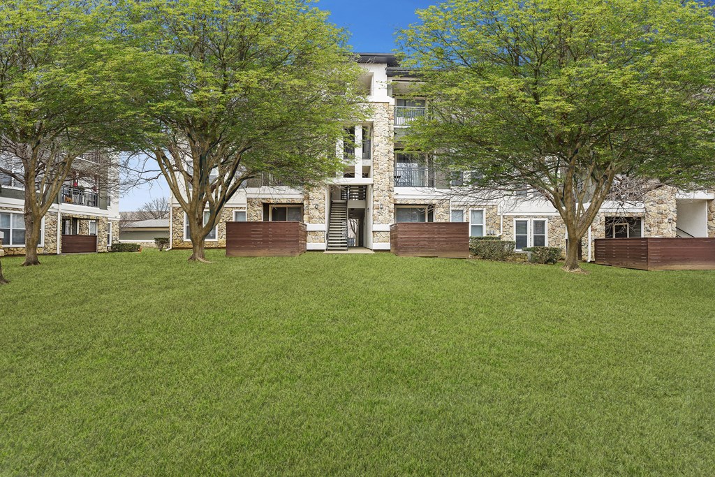 a large lawn in front of a house with trees