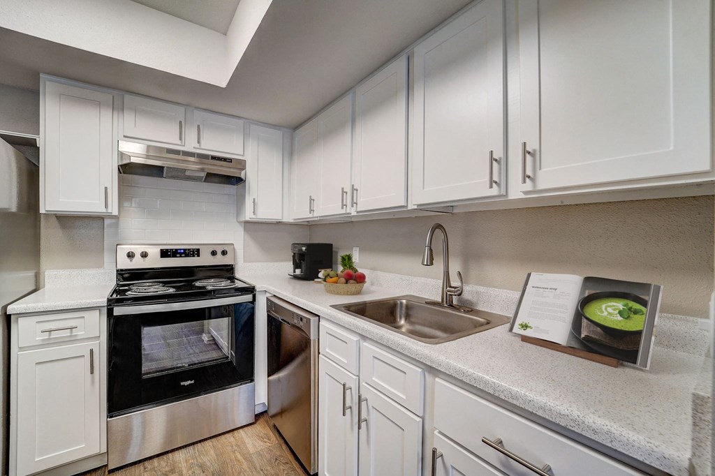 a kitchen with white cabinets and appliances and a sink