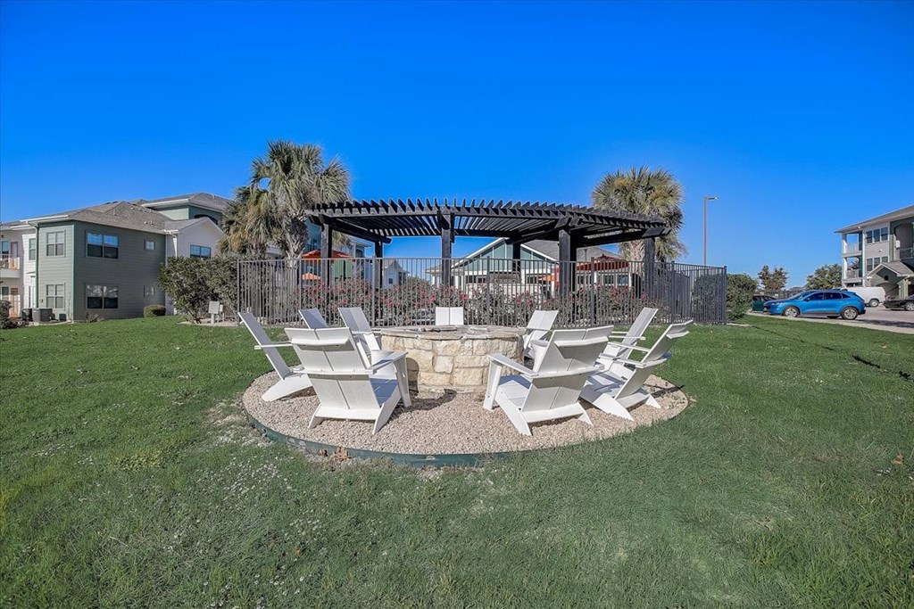 a fire pit with chairs and a pergola in a yard