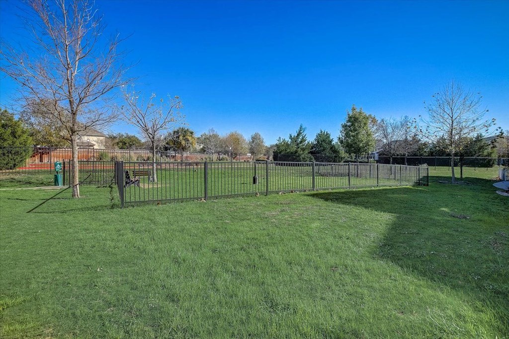 the dog park is fenced in with green grass