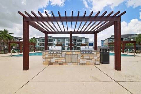 A wooden pergola is over a pool area.