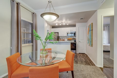 a dining room and kitchen with a glass table and chairs