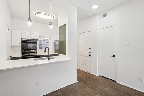 A kitchen with white cabinets and a white countertop with a sink.
