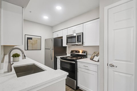 A modern kitchen with white cabinets and stainless steel appliances.