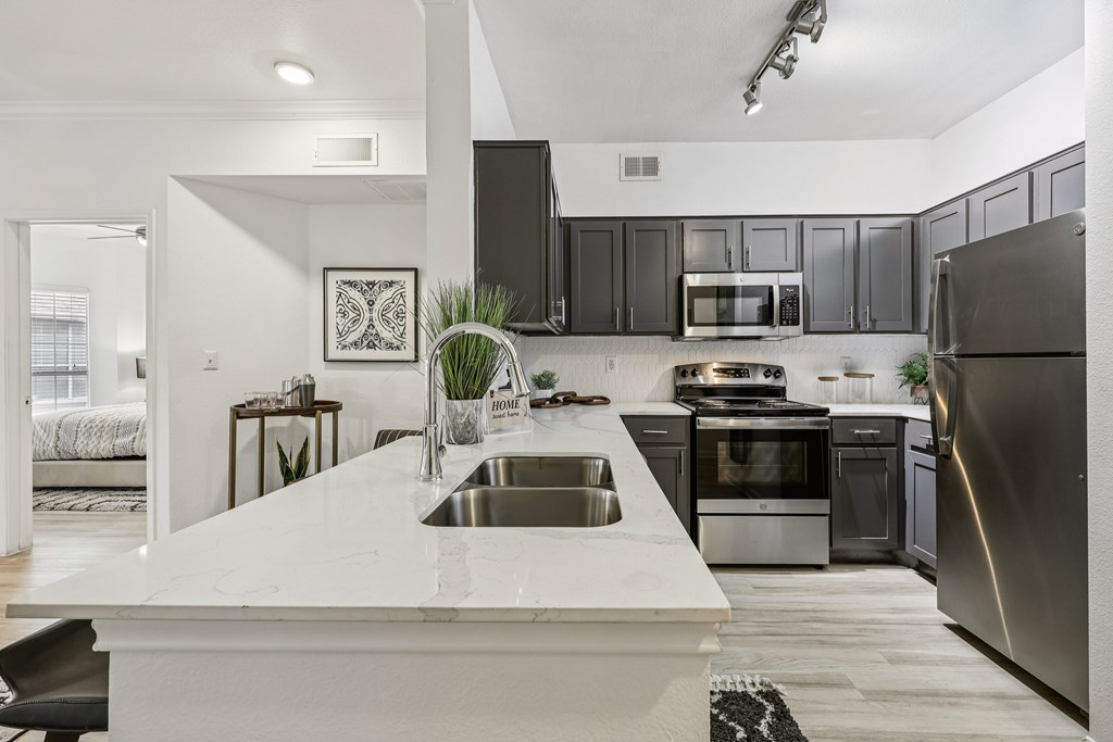 A modern kitchen with a white countertop and stainless steel appliances.