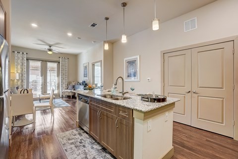 A kitchen with a large island and a refrigerator on the left.