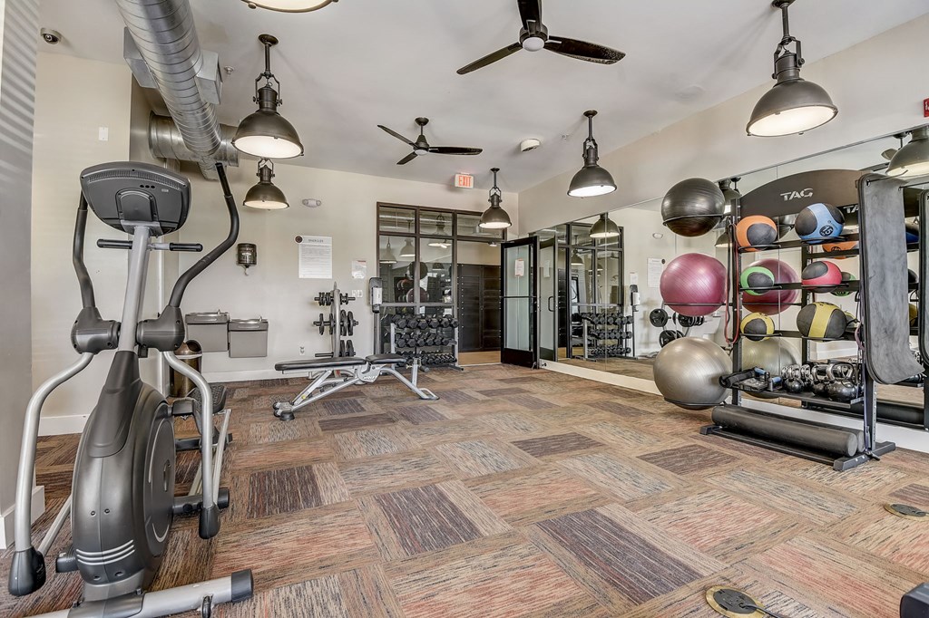 a gym with exercise equipment and weights on the floor and a wall of mirrors