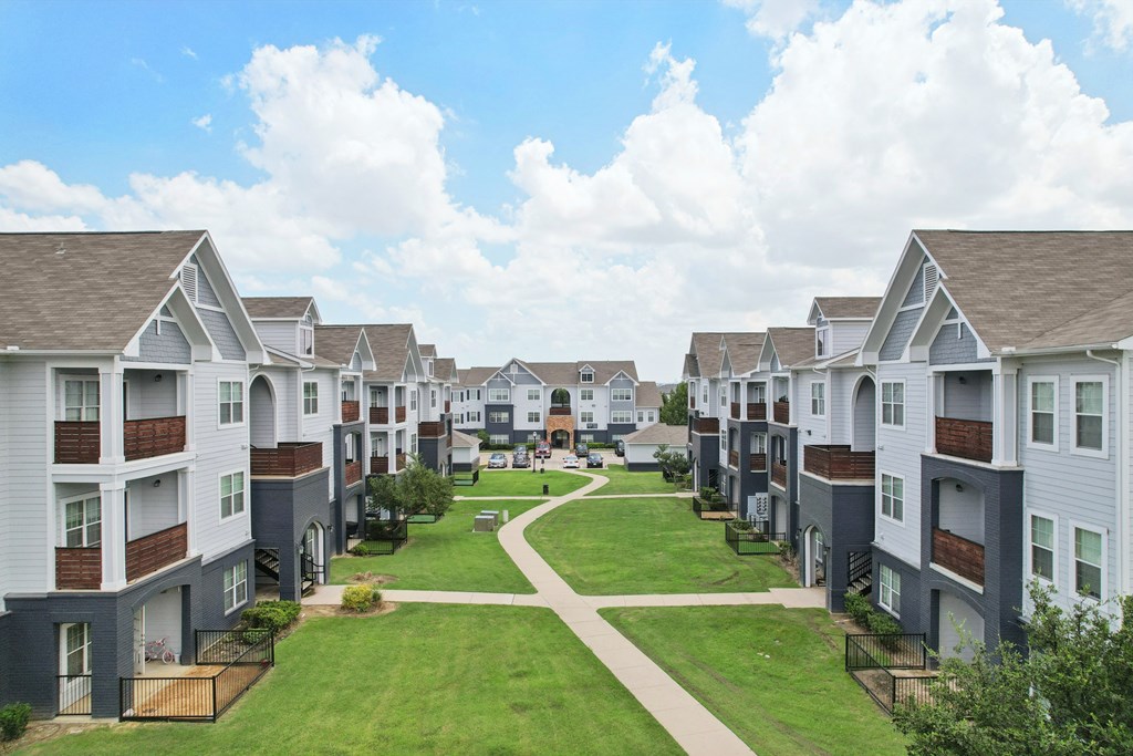 A row of modern townhouses with a grassy area in the foreground.