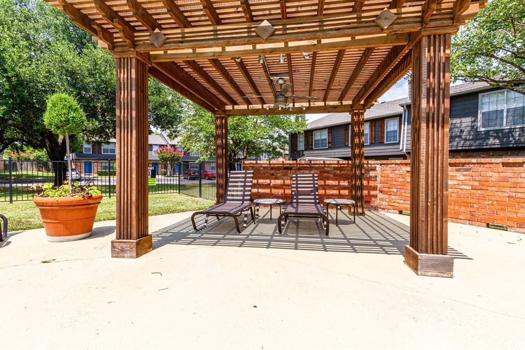 a wooden pergola with a table and chairs under it