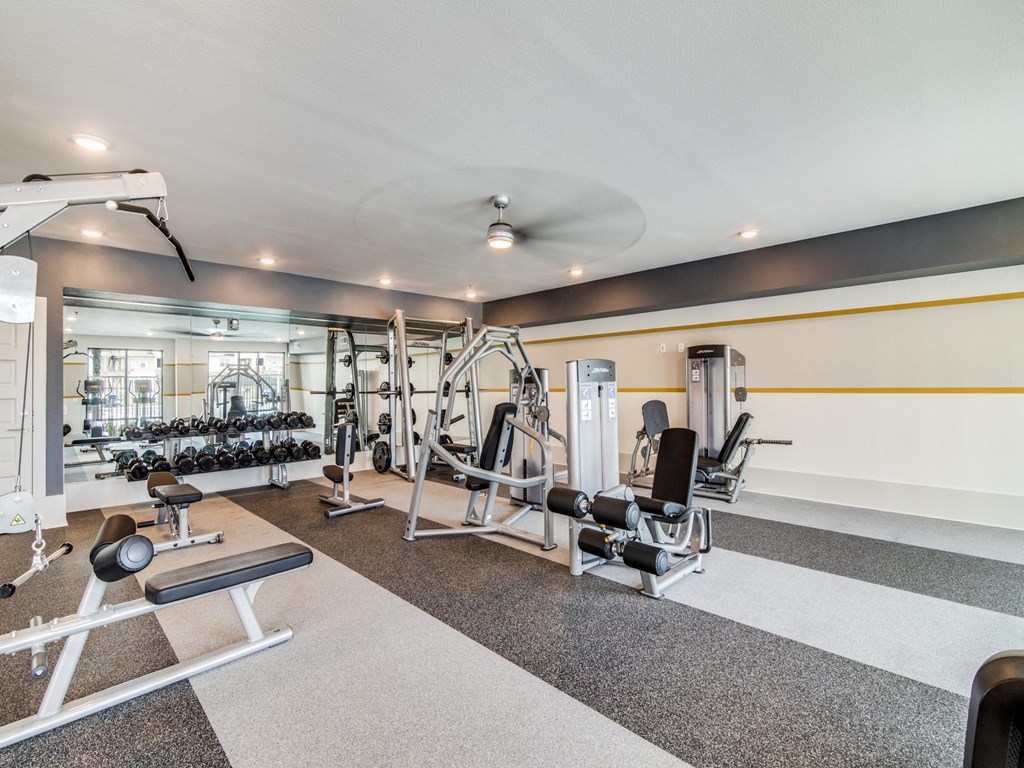 a gym with weights and cardio equipment in a building with white walls