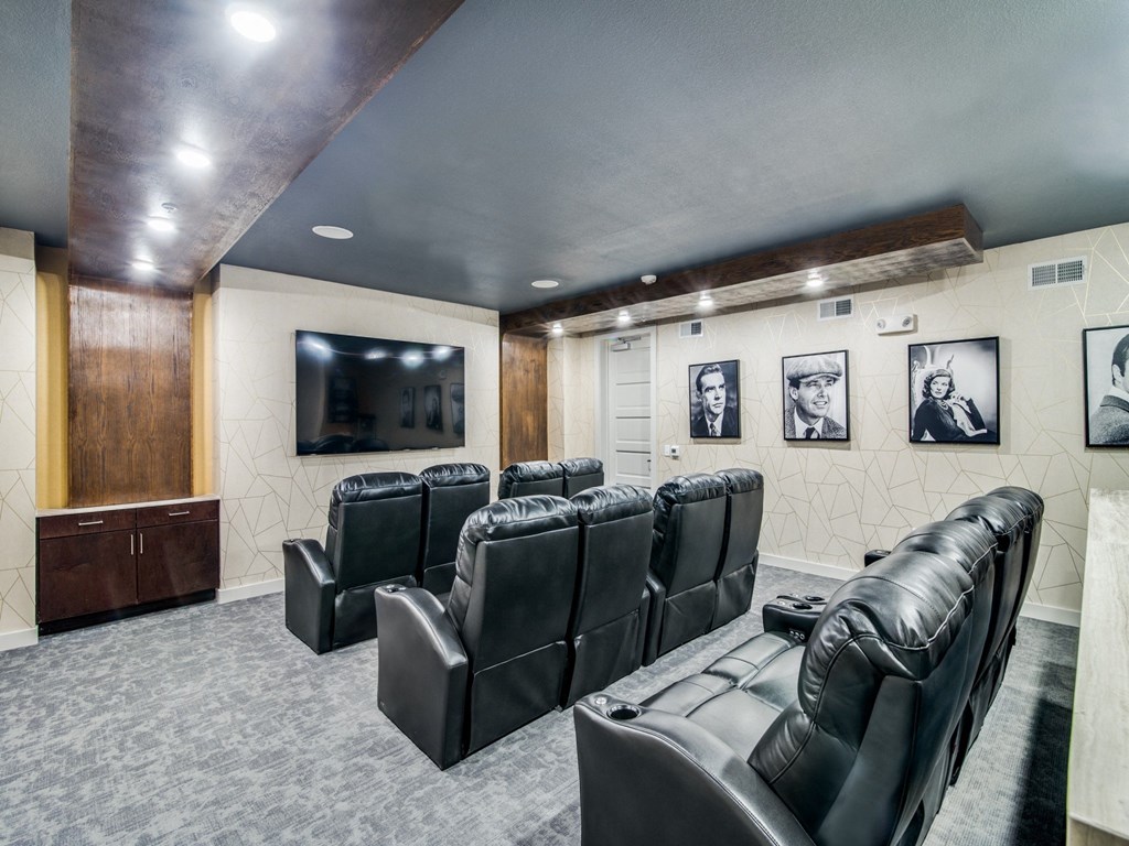 a theater room with leather chairs and a tv