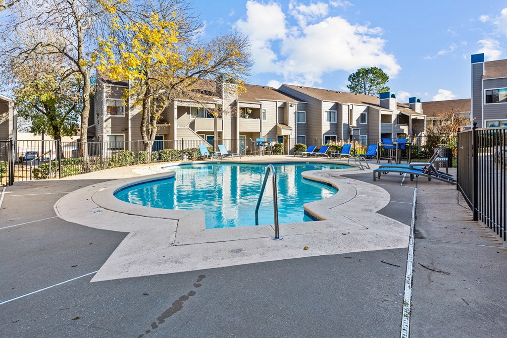 our apartments have a swimming pool with chairs and apartment buildings in the background