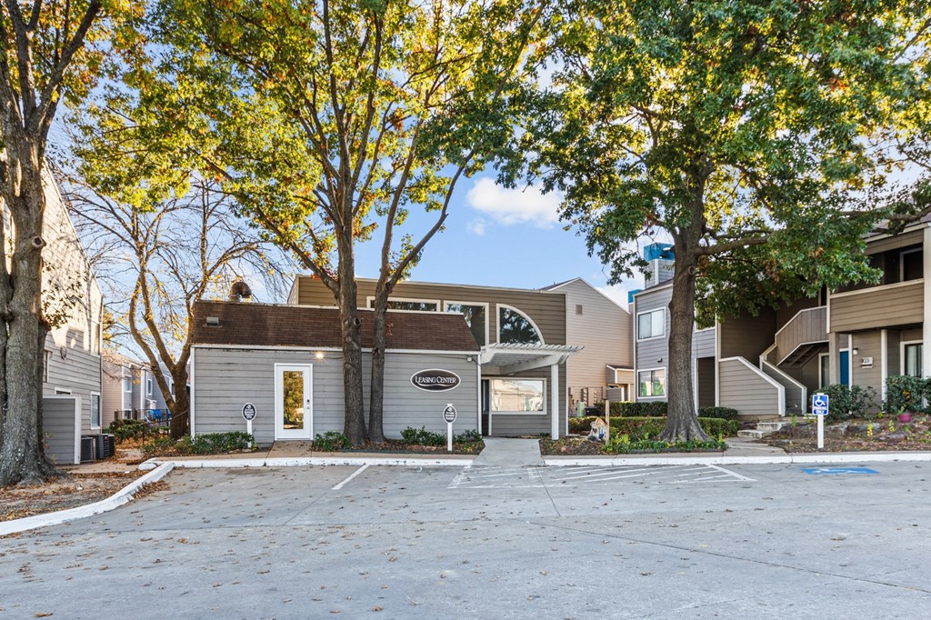 an empty parking lot in front of a building with trees