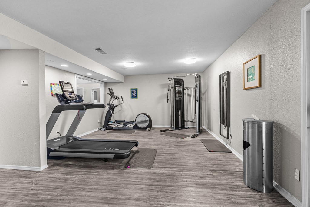 a gym with treadmills and exercise equipment in a home with white walls