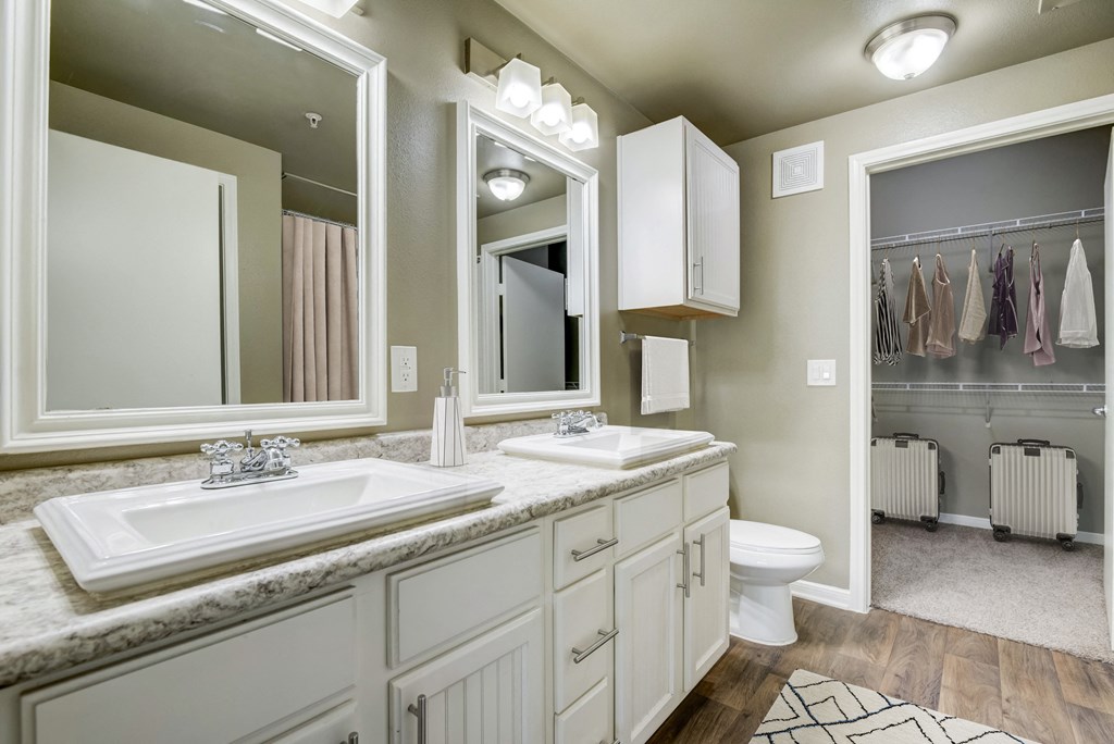 a bathroom with two sinks and a toilet and a mirror