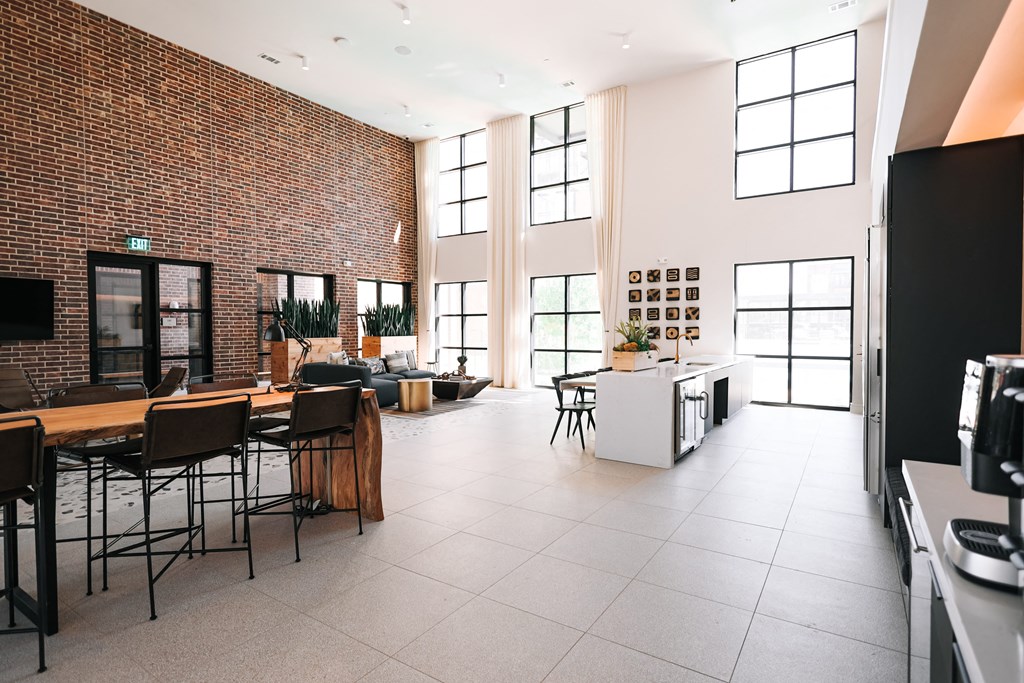 a large living room with a kitchen and dining area and tall windows