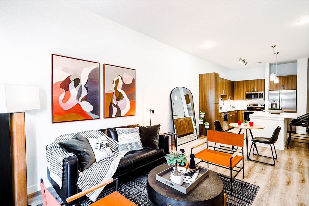 a living room with a couch and a table and a kitchen in the background