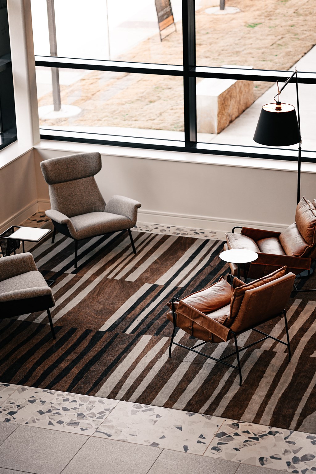 a living room with chairs and a rug and a large window