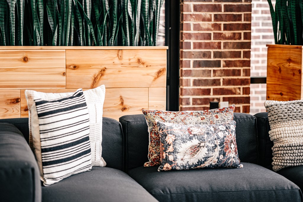 a couch with pillows in front of a brick wall