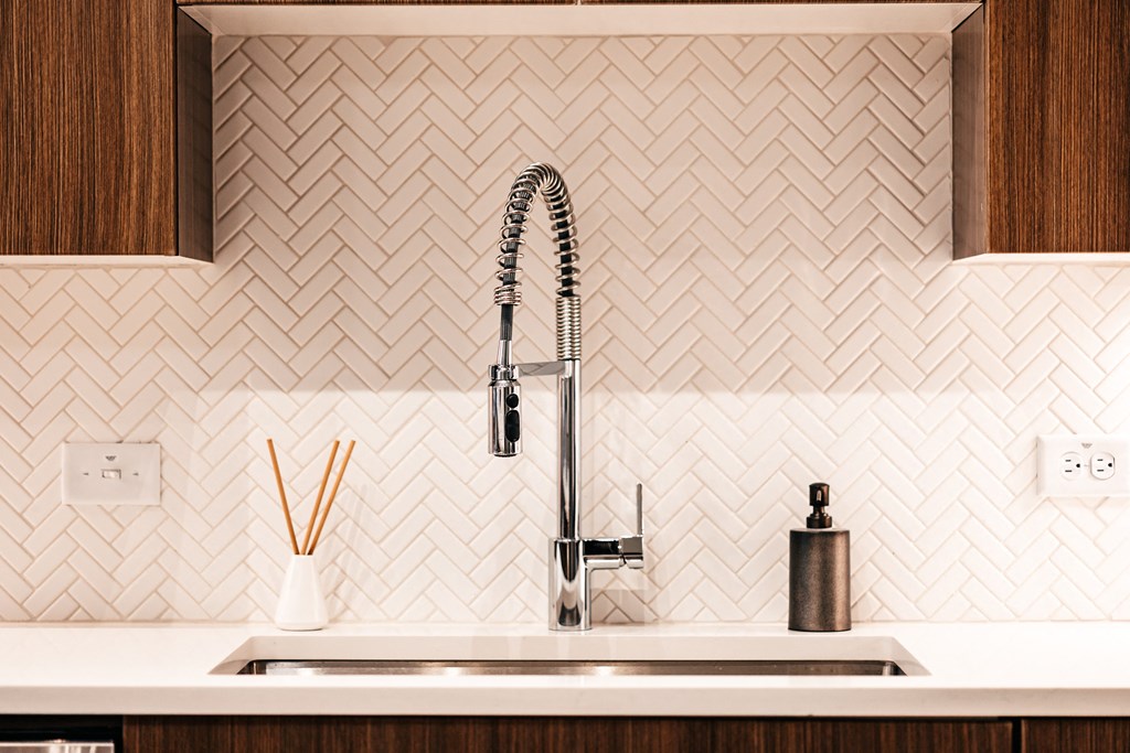 a kitchen with white tile and a sink and a faucet