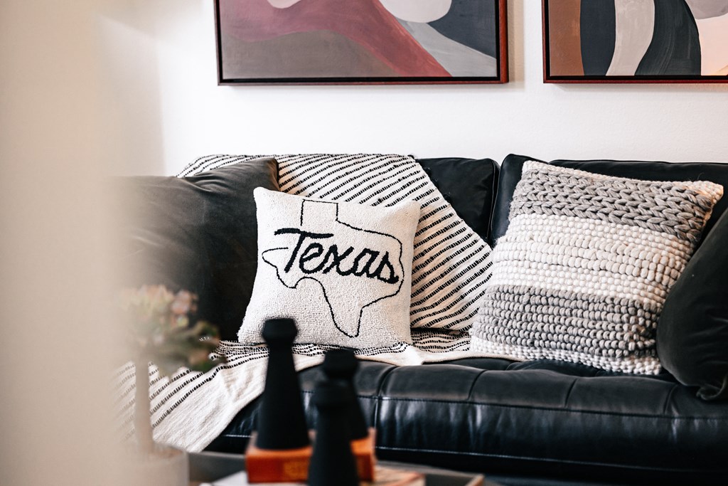 a living room with a black couch and pillows on it
