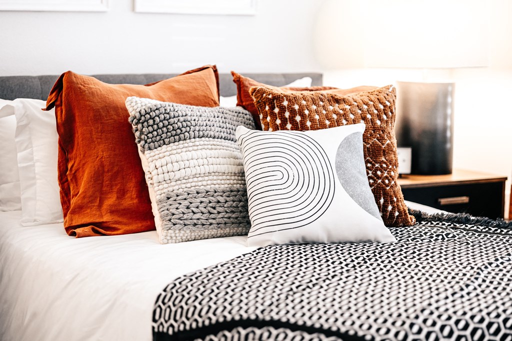 a bed with many pillows on it and a black and white blanket