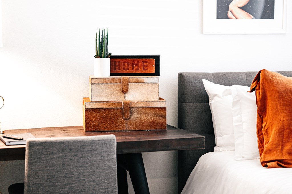 a bedroom with a bed and a table with a stack of boxes on it