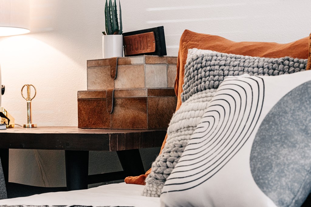 a bedroom with a bed with pillows and a desk with a cactus