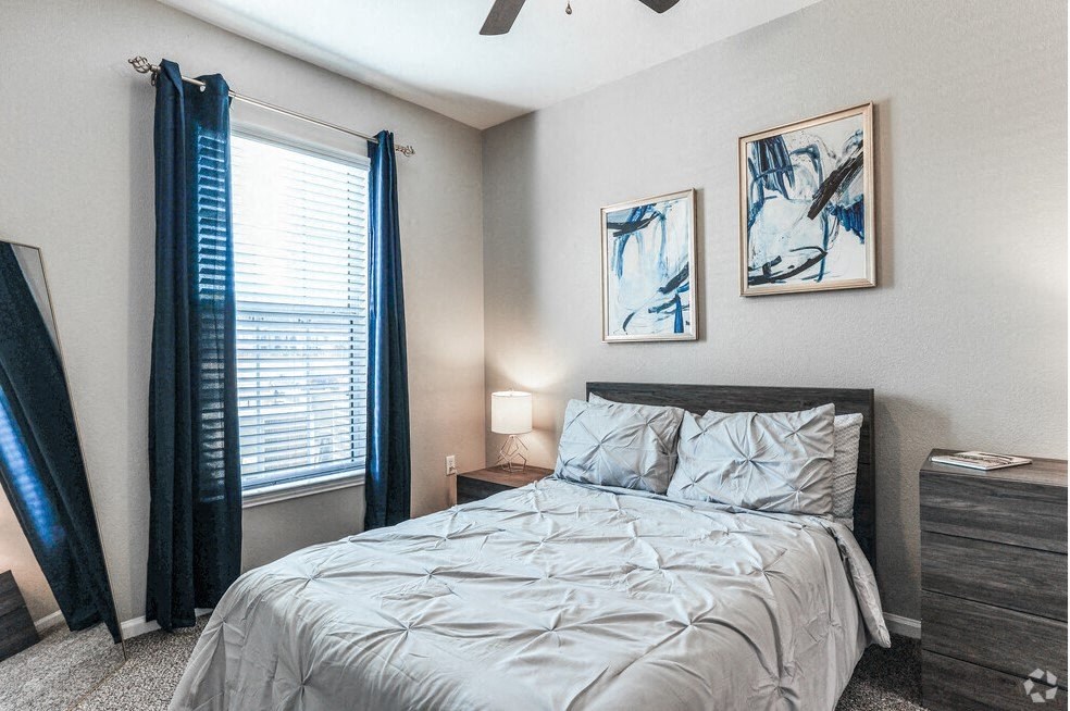 a bedroom with a bed and a window with blue curtains