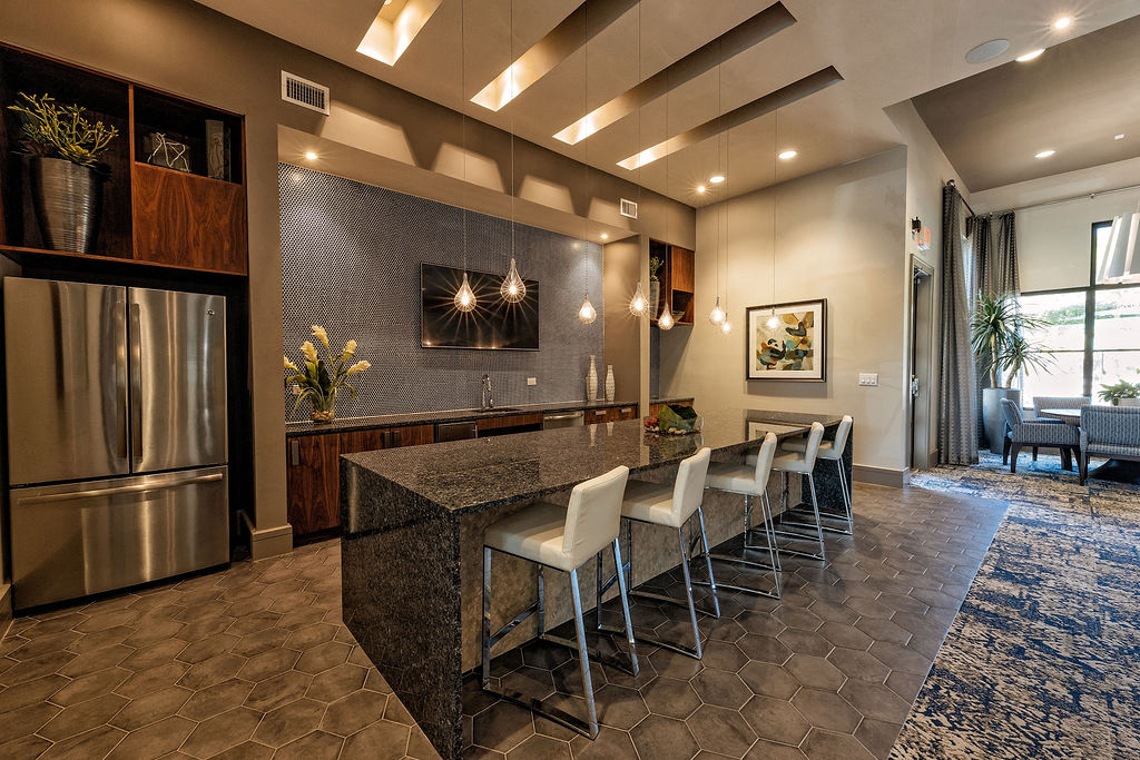 A modern kitchen with a refrigerator, island, and chairs.
